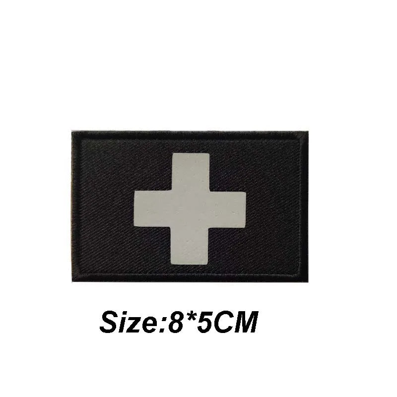 Black tactical morale patch with a white cross symbol, measuring 8 by 5 centimeters.