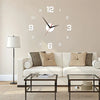 A frameless acrylic digital wall clock with Roman numerals is mounted above a modern sofa and coffee table.