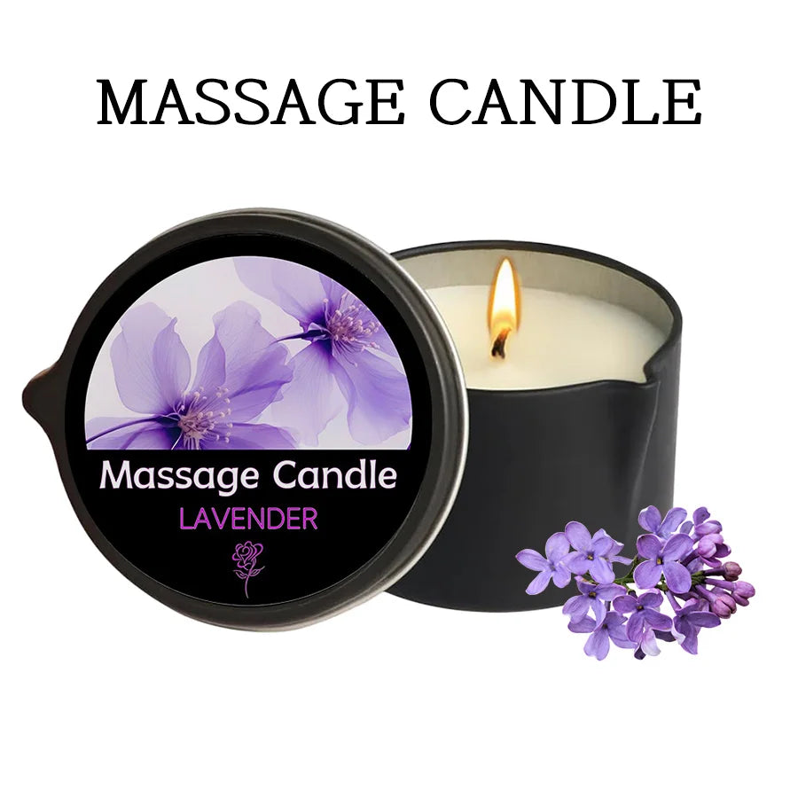 A black jar candle labeled Massage Candle Lavender with a lit wick and purple lavender flowers nearby.