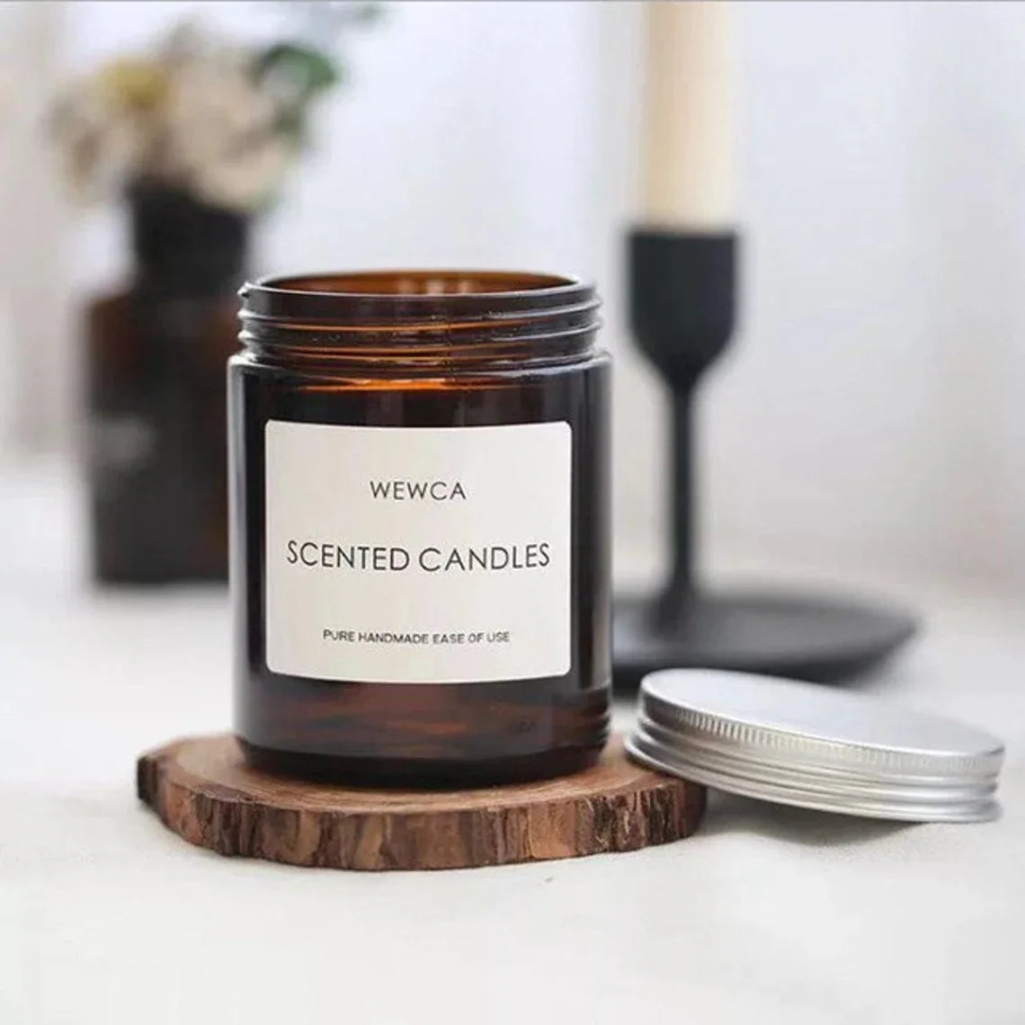 Amber glass candle jars with airtight metal lids displayed on a wooden coaster.