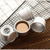 A set of five white non-stick round cake molds with removable bases resting on a dark wooden surface and a checkered cloth.