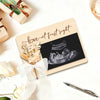 A wooden ultrasound photo frame with a ribbon, featuring an ultrasound image and handwritten text for a pregnancy announcemen