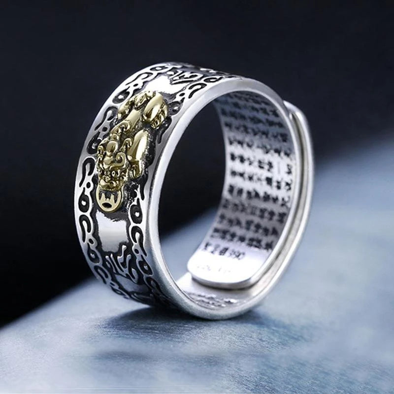 Silver ring featuring a pixiu design with gold coin details on a dark background.