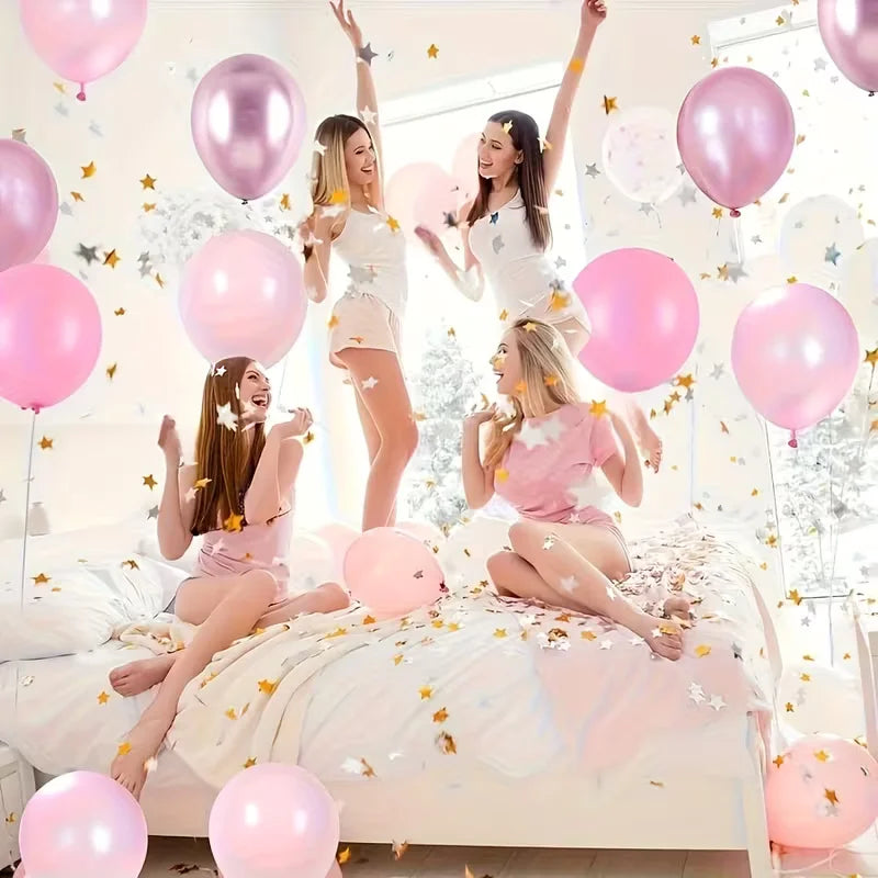 A woman is surrounded by pink balloons and confetti in a bright room, celebrating with joy.