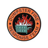 An enamel pin featuring a stylized fire above a green dumpster and the text Dumpster Fire Response Team