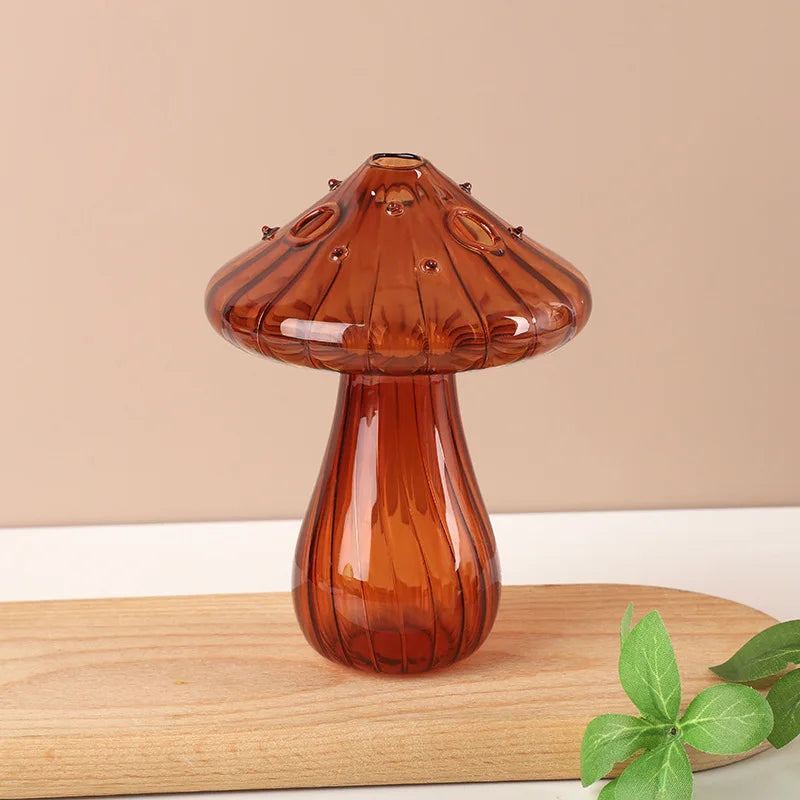 A glossy amber glass vase shaped like a mushroom, resting on a light wooden surface.