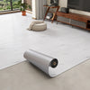 Roll of 3D textured wood grain self-adhesive flooring film displayed on a light floor.