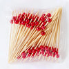 A clear plastic bag filled with numerous red glass marble fruit skewers made of bamboo sticks.