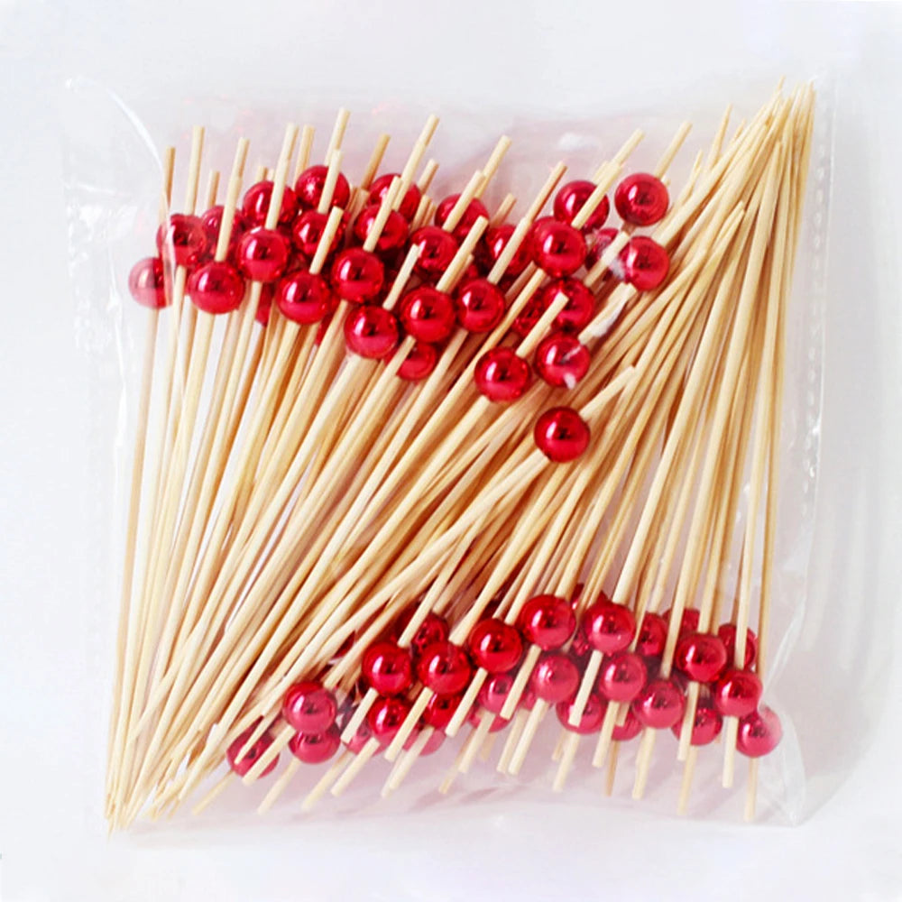A clear plastic bag filled with numerous red glass marble fruit skewers made of bamboo sticks.