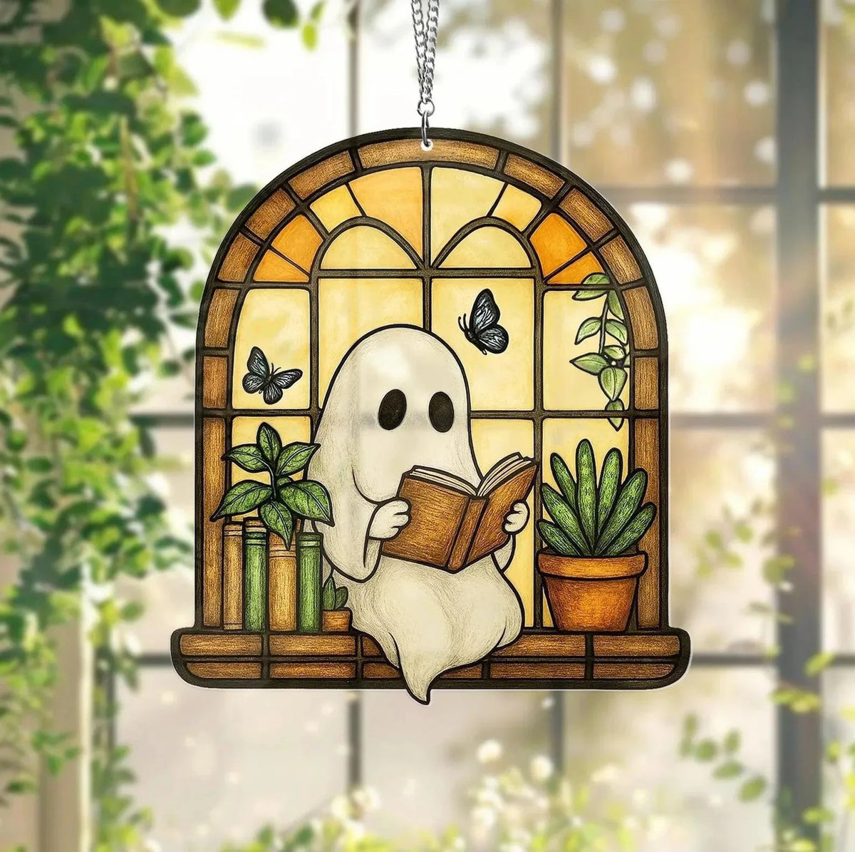 A white ghost figure holding an open book is displayed in a wooden window frame decorated with green plants and butterflies.