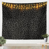 A dark tapestry featuring a leopard print pattern illuminated by warm string lights.