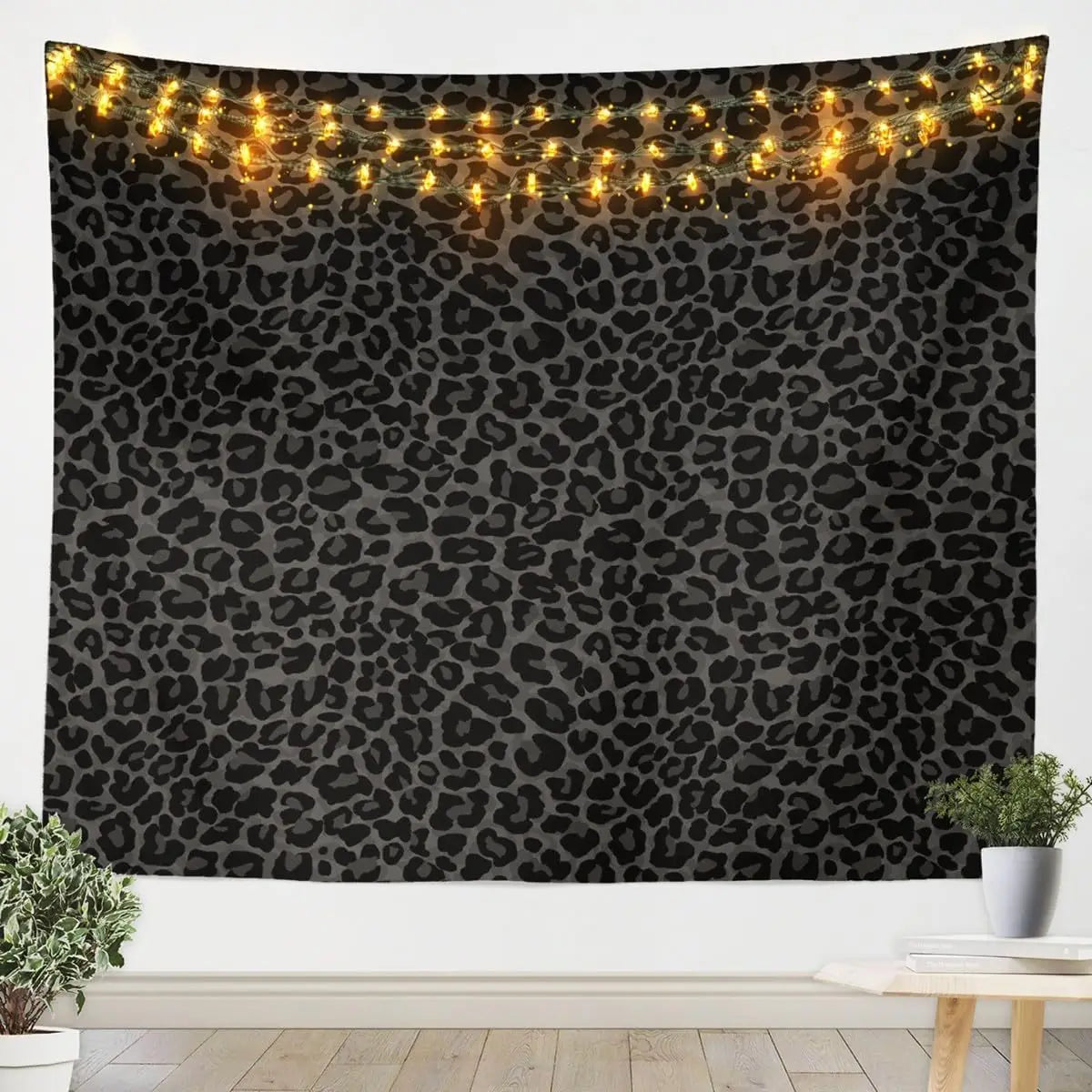 A dark tapestry featuring a leopard print pattern illuminated by warm string lights.
