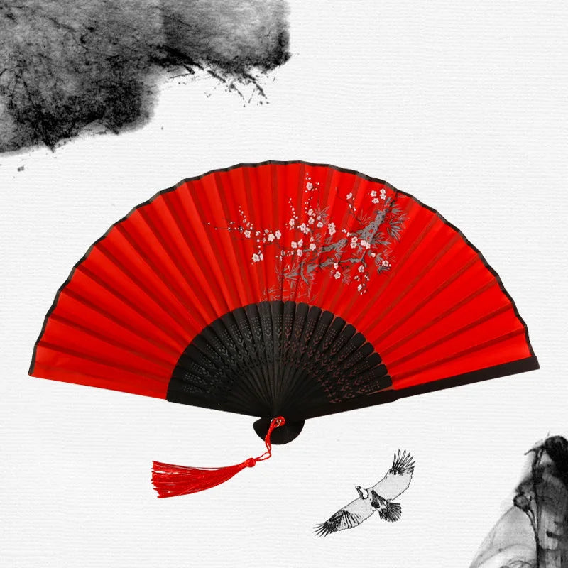 A red and black vintage bamboo folding hand fan with delicate floral accents.