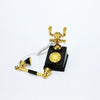 A vintage rotary desk phone miniature decor with a gold handset and black base.