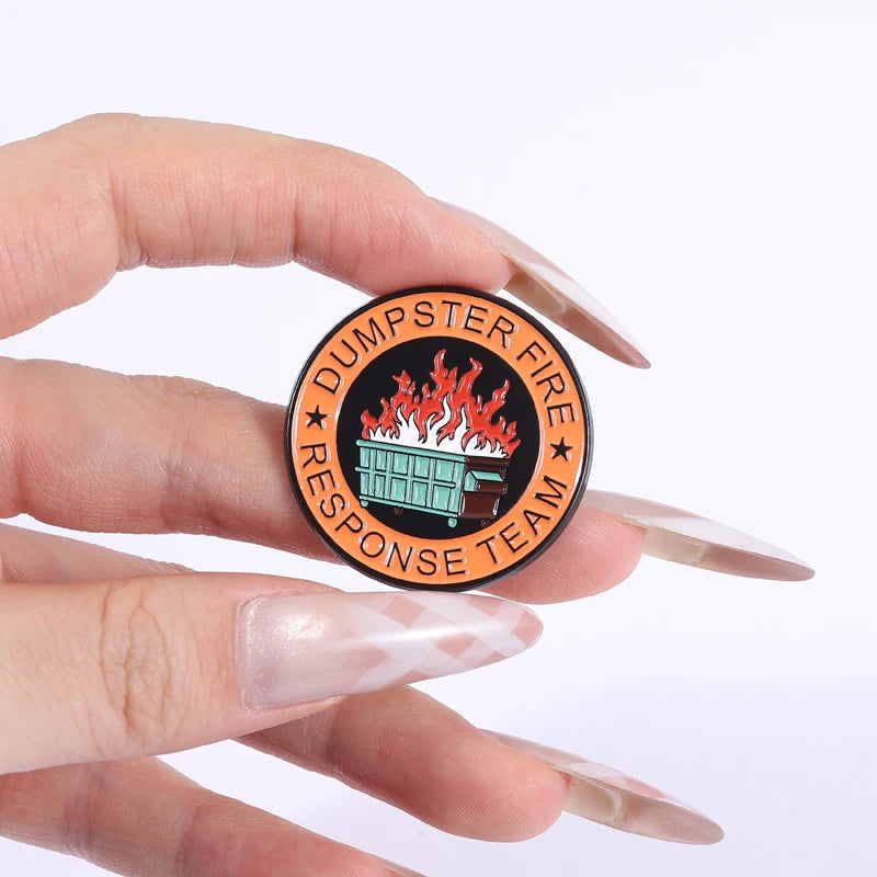 An enamel pin featuring a stylized fire and dumpster design for the Dumpster Fire Response Team.