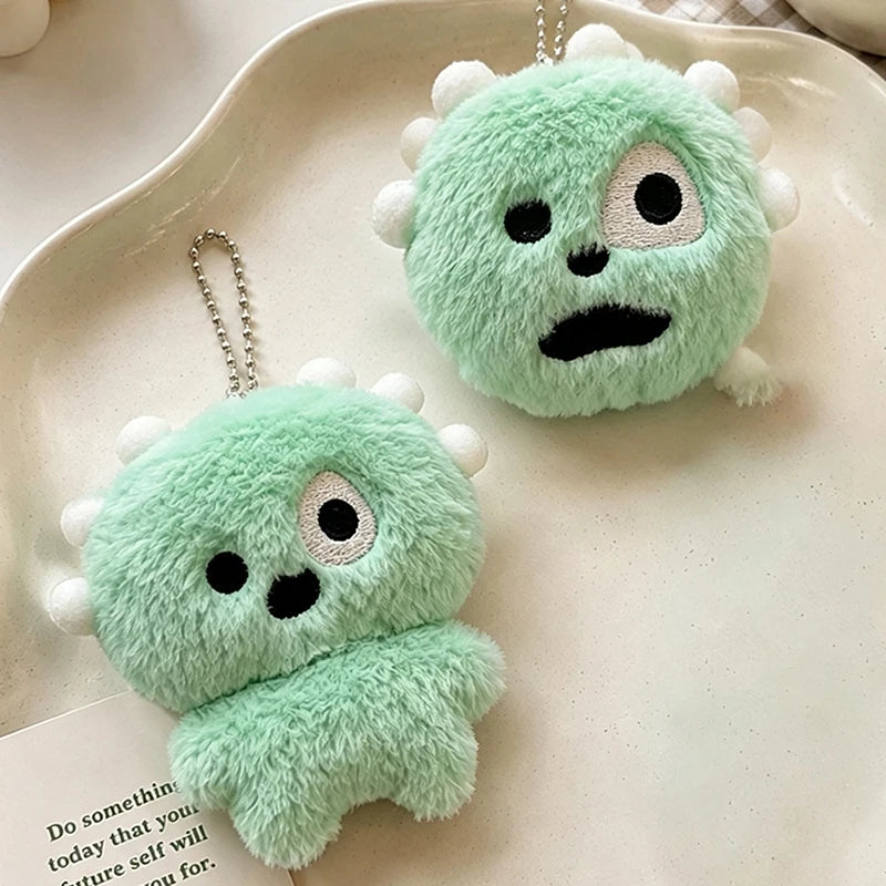 A pair of light green fuzzy plush toys shaped like monsters or creatures, used as keychains with clear photo card holders.