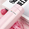 A pink electric hair styling tool labeled Lucas resting on a box with pink hair ties.