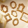 A collection of vintage gold DIY shadow box frames and ornate picture frames on a light background.