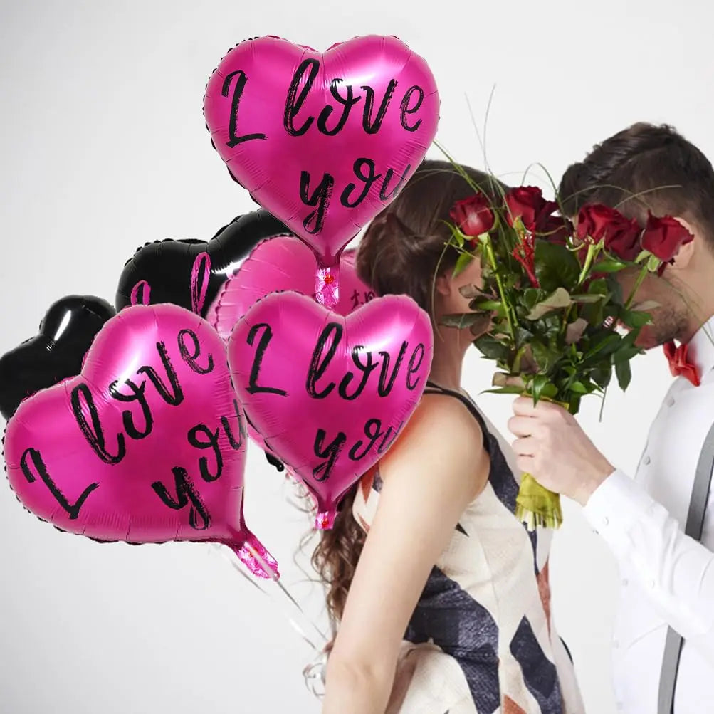 A set of ten pink and black heart-shaped balloons is held by a couple.