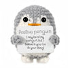 A gray crocheted penguin toy holding a white card with the message I may be a tiny penguin but I believe in you go do your th