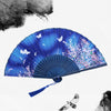A blue and purple vintage bamboo folding hand fan with white butterflies and floral accents.