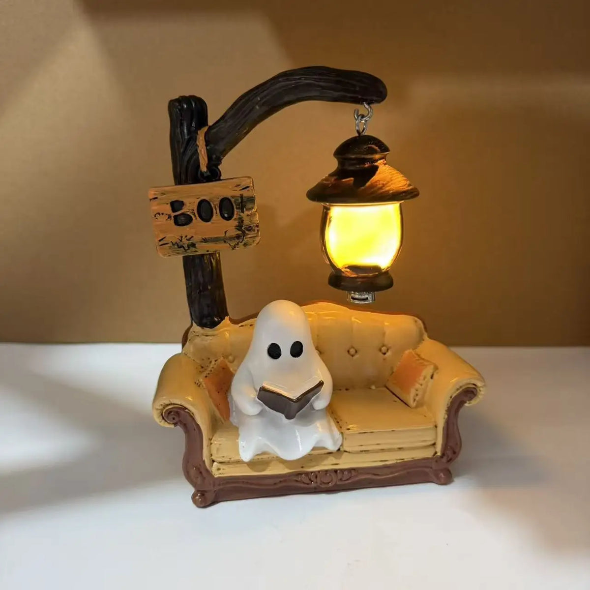A figurine of a ghost reading a book is displayed with a hanging lantern decor.