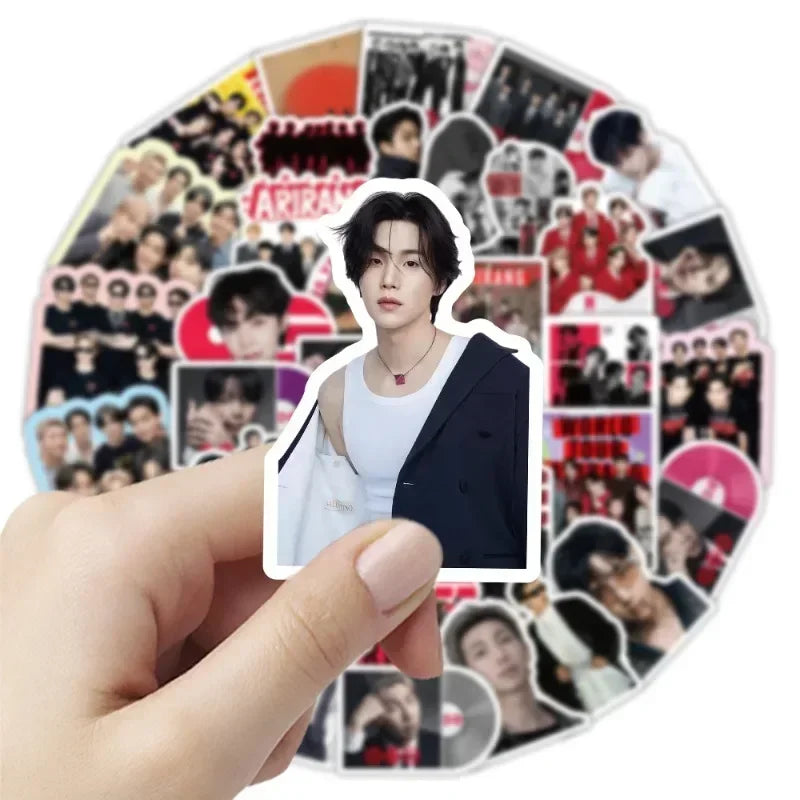 A hand holds a round sticker pack featuring various photos of K-pop idols and related graphics.