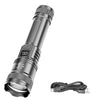 A silver compact flashlight with a textured lens and battery compartment is shown next to its charging cable.