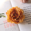 A close-up of a golden orange flower decoration on a page with text.