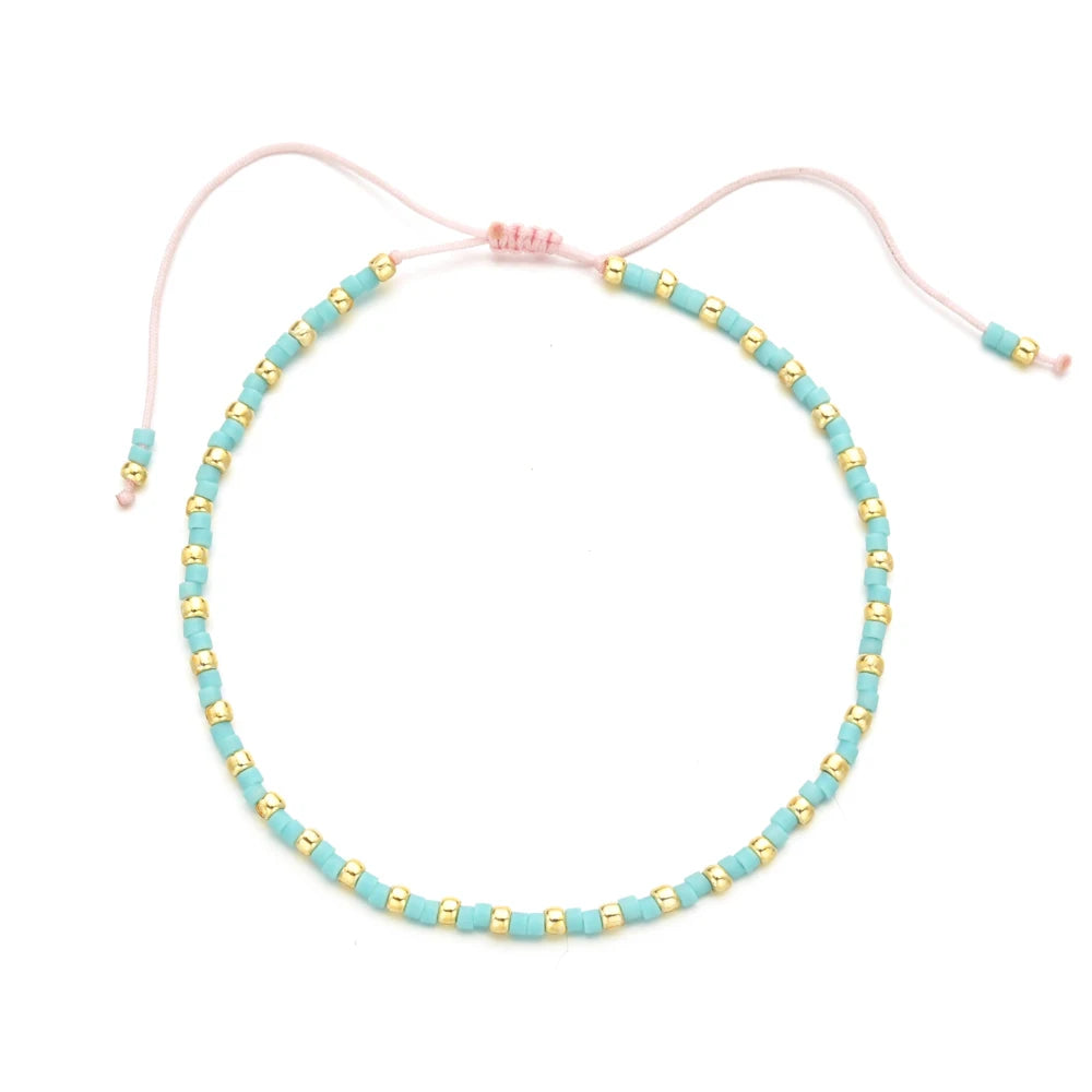 Handmade boho glass bead bracelet with adjustable cord featuring light blue beads and pink cord.