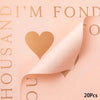 A sheet of peach-colored wrapping paper with gold text and a heart cutout, showing the texture and design.