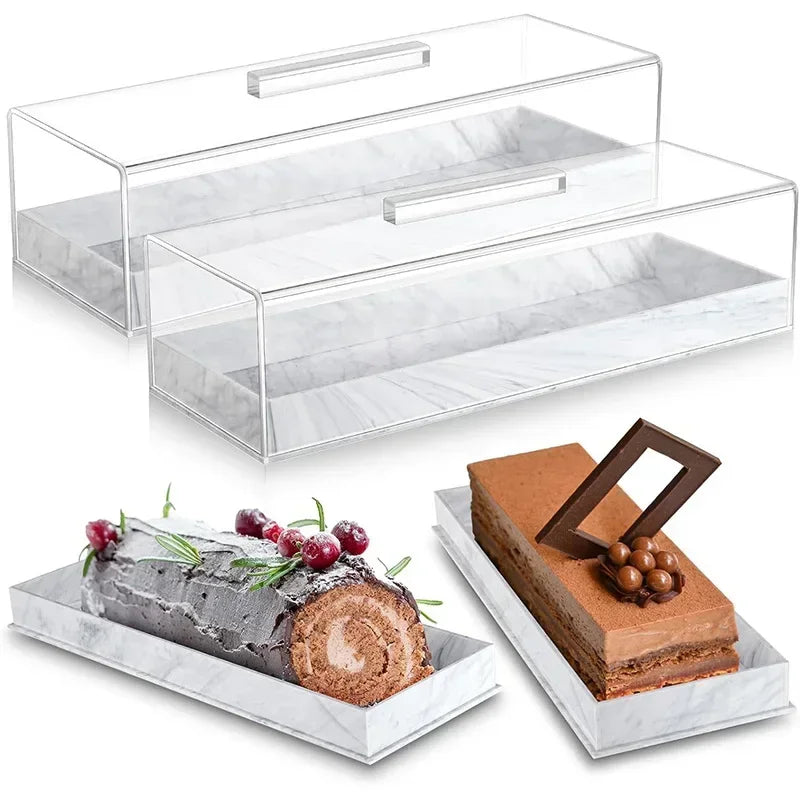 Clear acrylic cake stand with a lid displaying rectangular marbleized desserts on a white marble tray