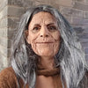 A close-up portrait of an elderly woman with long gray hair and wrinkled skin.