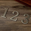 Magnetic silver house numbers 123 placed on a dark wooden surface.