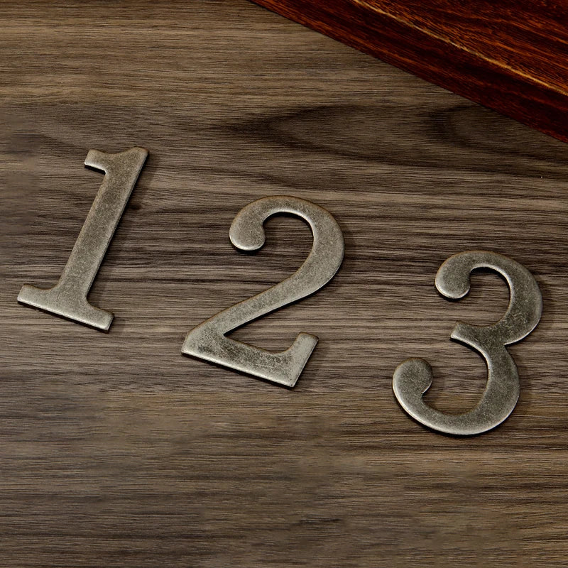 Magnetic silver house numbers 123 placed on a dark wooden surface.