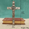 A bronze crucifix featuring a figure of Christ with a St. Benedict medal and INRI inscribed on the cross, displayed above a r
