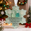 A clear sea glass ornament shaped like a snowflake with a silhouette of two people inside, hanging on a white background.