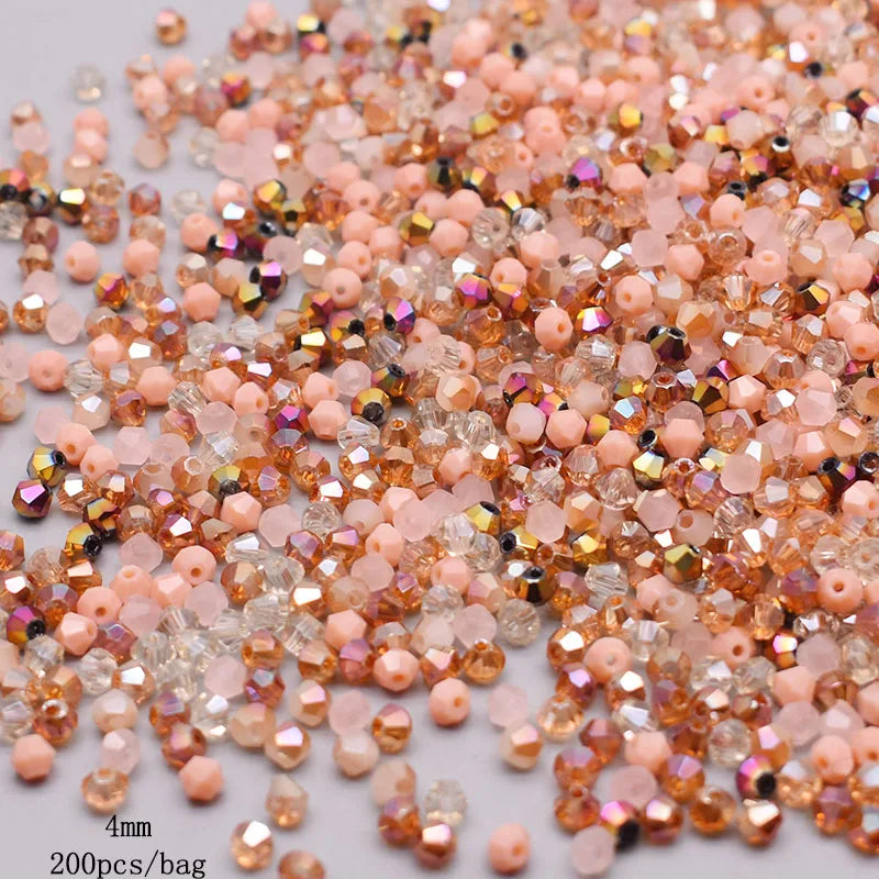 A close-up of mixed colored faceted bicone glass beads in shades of pink, orange, and amber.