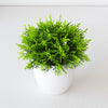 Un vibrant arbre bonsai artificiel vert dans un pot blanc, exposé sur une surface blanche.
