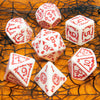 A collection of seven white and red polyhedral dice scattered on a textured orange surface.
