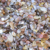 A close-up view of natural tumbled gemstone chips in various shades of pink, purple, white, and yellow.