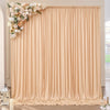 A floor-to-ceiling beige pleated fabric backdrop with floral arrangements used as decoration.