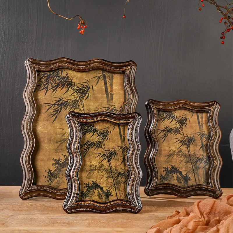 Two antique resin photo frames with distressed gold and brown finishes displayed on a wooden surface.