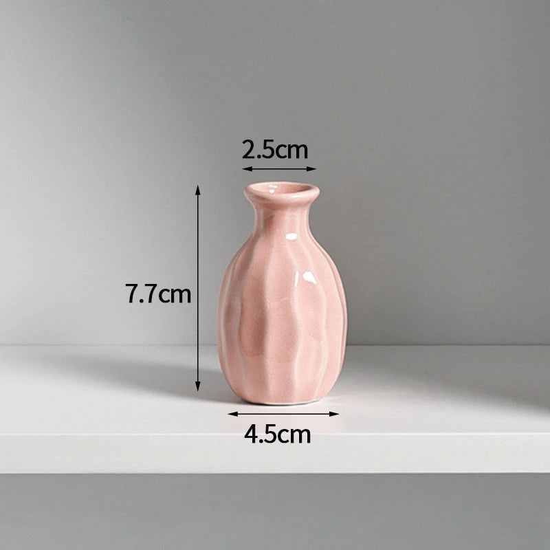A pink ceramic mini vase with a rounded body and narrow neck, shown against a light gray background.