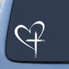 A white heart with a cross design decal on a dark car window.