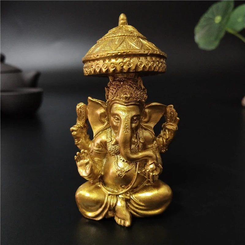 A golden bronze statue of Ganesha Buddha seated in a meditative pose with an ornate crown.