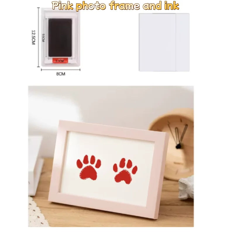 A pink photo frame and ink kit showing a wooden frame with red paw prints on white paper.