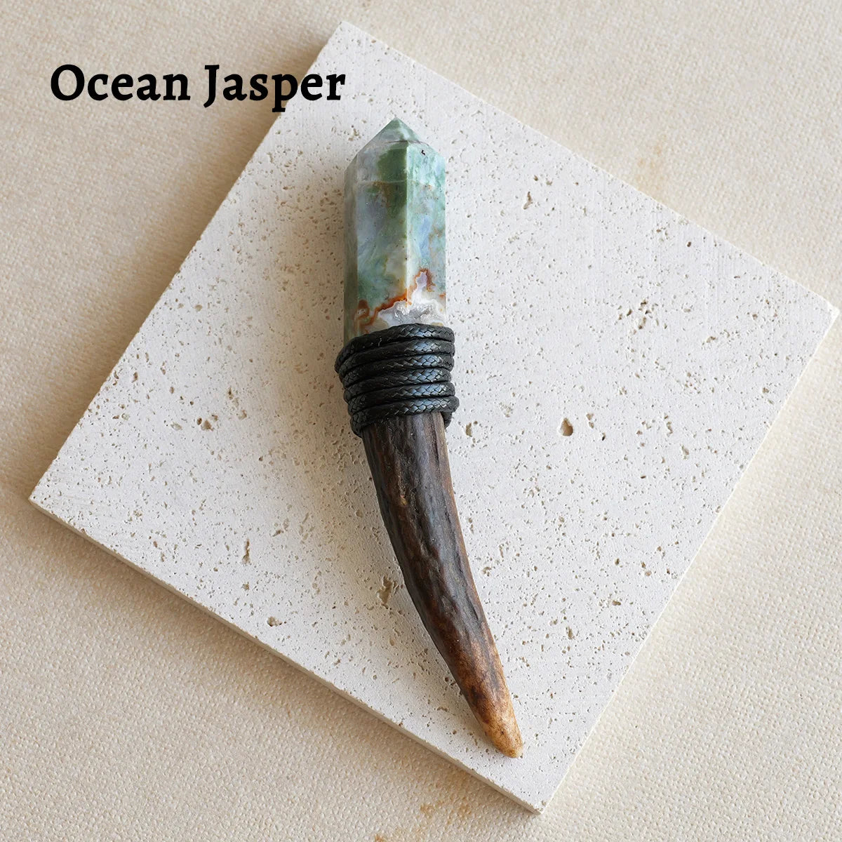 An Ocean Jasper scepter wand with a green crystal top and dark wood handle resting on a white card.
