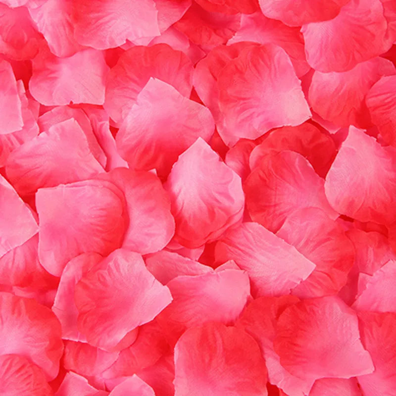 A close-up of vibrant pink and red silk rose petals scattered for decoration.