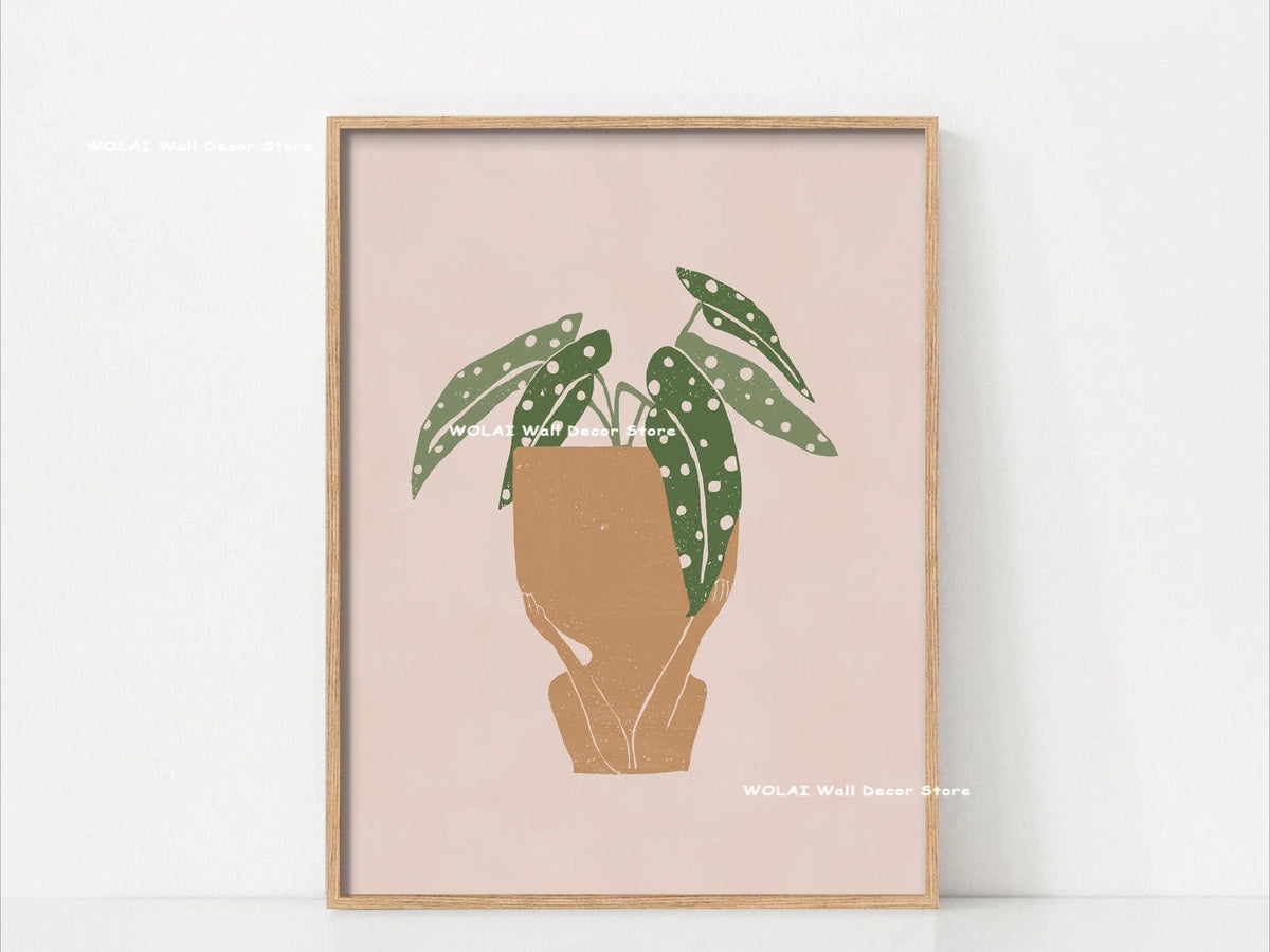 Wall art featuring a watercolor illustration of a philodendron plant in a terracotta pot on a light pink background.